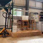 woman stands beside chestnut milling machine at Rural Action