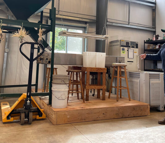 woman stands beside chestnut milling machine at Rural Action