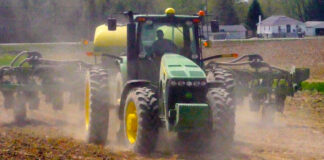 tractor plowing field kicking up dust