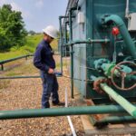 Largest well owner in Appalachia charts path to net zero by looking for leaks A worker holds a handheld gas detector up to a gas separator at a well pad