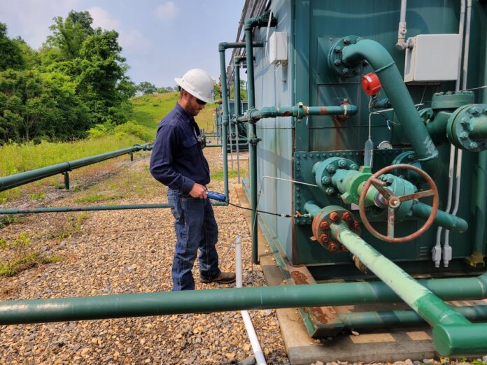 diversified energy methane sniffer A worker holds a handheld gas detector up to a gas separator at a well pad