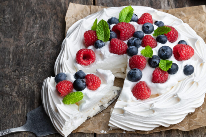 Pavlova meringue nest with berries and mint leaves on wooden tab
