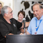 two white men shake hands behind a lecturn