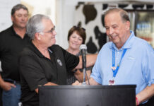 Longtime Ohio State Fair general manager retires two white men shake hands behind a lecturn