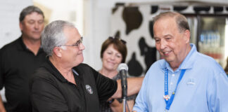Longtime Ohio State Fair general manager retires two white men shake hands behind a lecturn