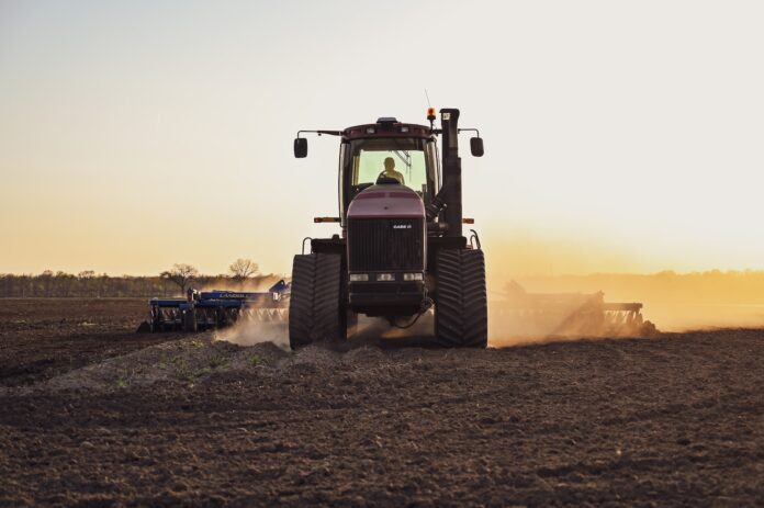 a tractor in a field with dust trailing it