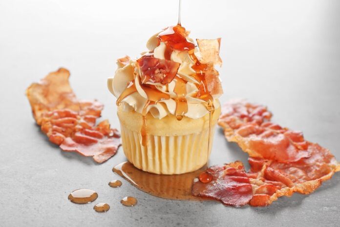 Pouring maple syrup onto cupcake with bacon on table Maple bacon cupcakes