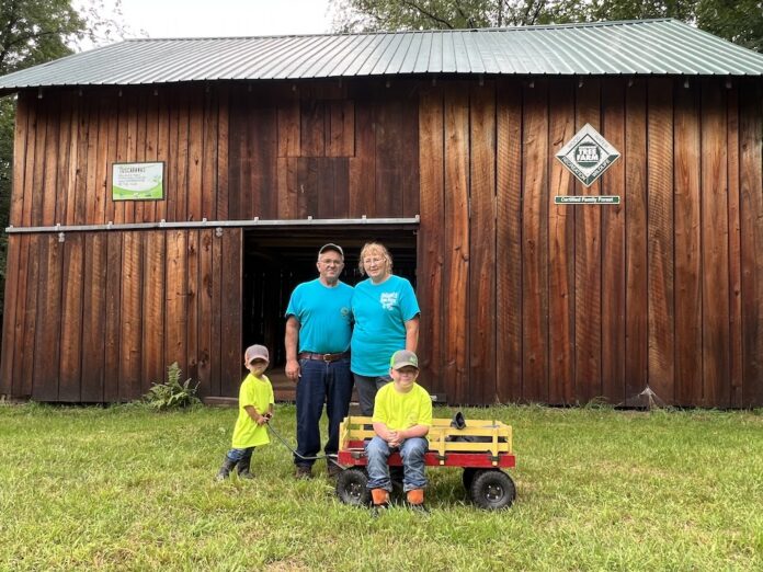 post boy tree farm 3 A man, a woman and two boys stand in front of a barn.