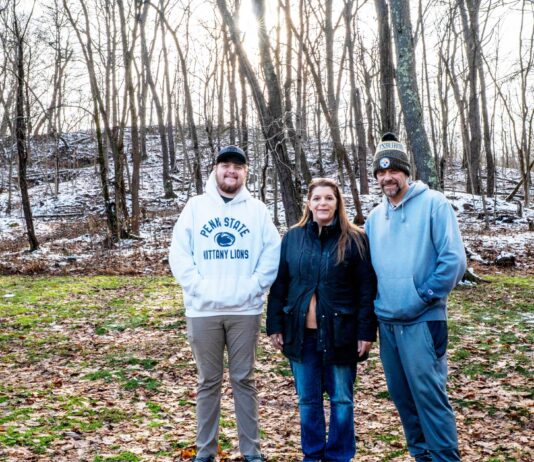 Tannar, Kimberly and Tom Barton stand in their backyard in Alicia, Pennsylvania on Dec. 7, 2025. The former Robena Coal Mine site is further up the hill.